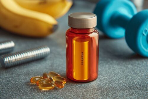 Bouteille de suppléments, capsules et haltères bleus sur surface grise